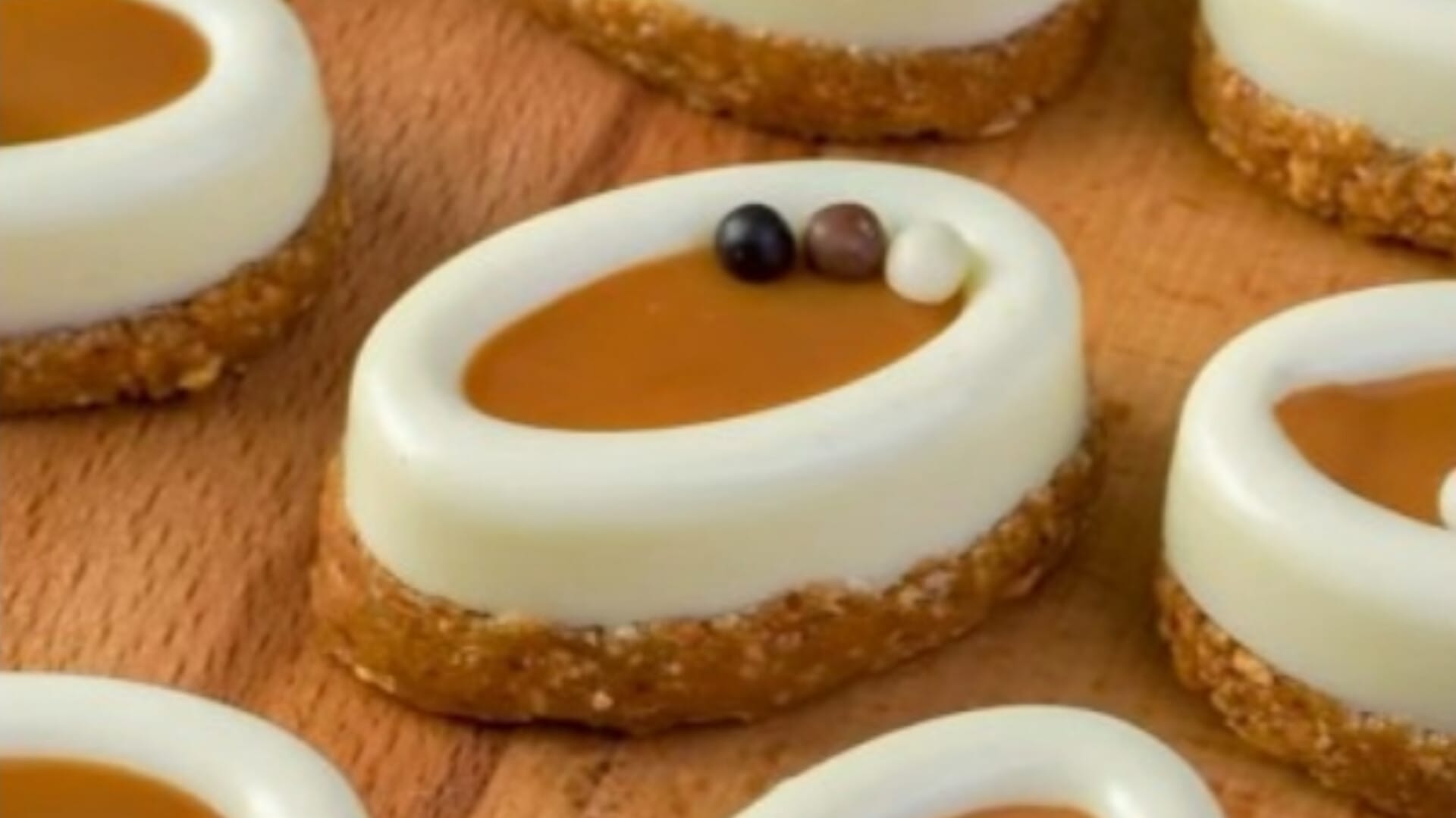 دسر بیسکویتی حلقهای با لایه کرم سفید شکلاتی، کارامل و تزیین شکلات؛ مناسب مهمانی و عصرانه