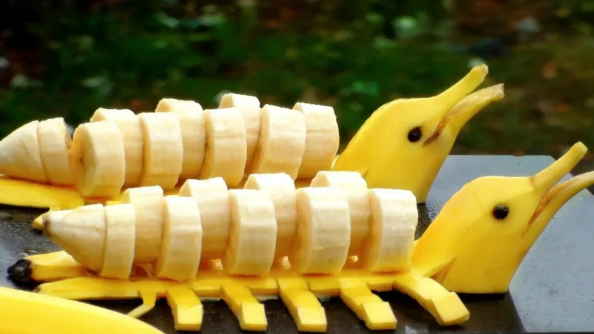 تزیین میوه آسان و خلاقانه با موز که به شکل دو دلفین زیبا در کنار هم قرار گرفتهاند.