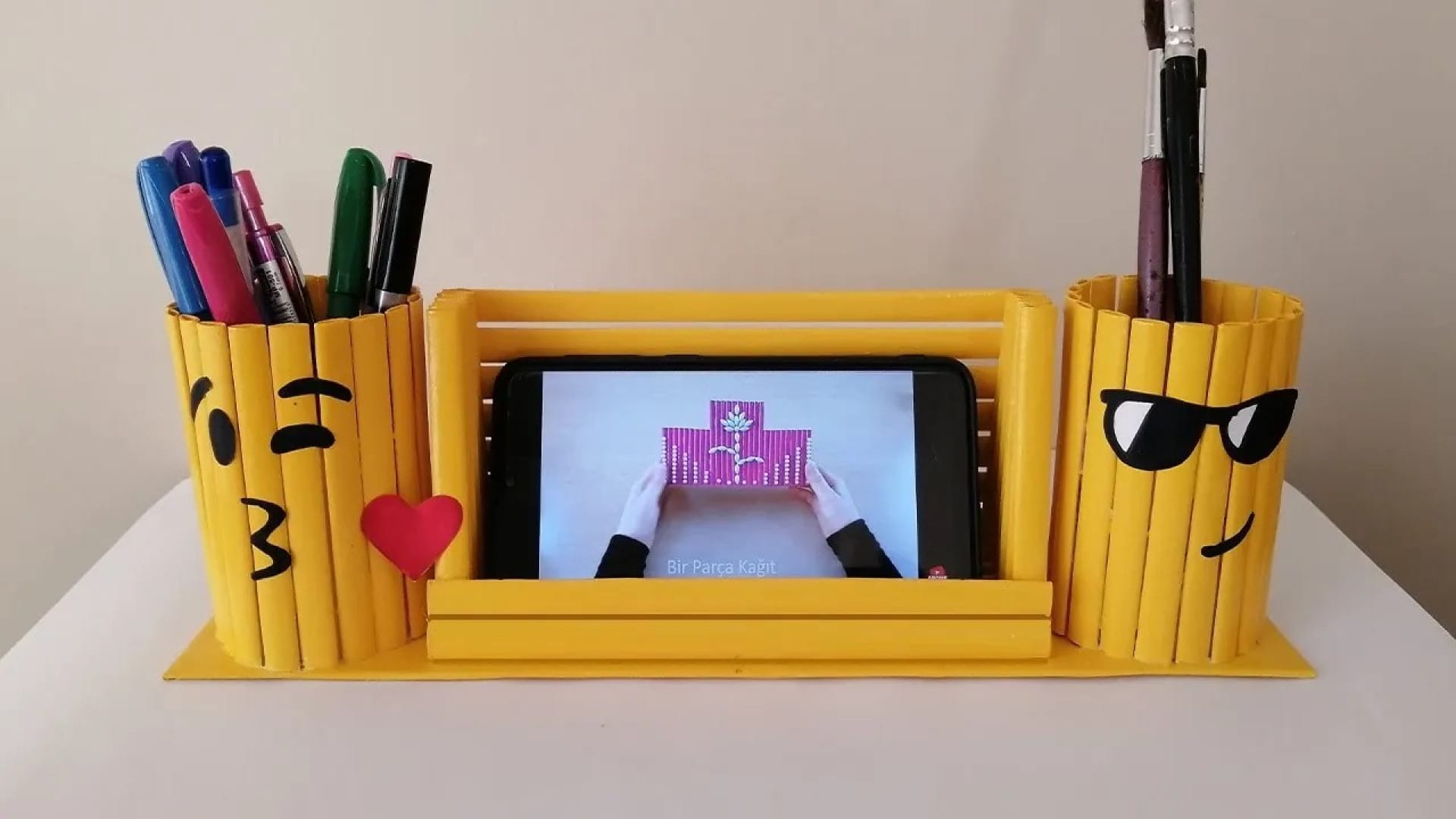 جامدادی رومیزی فانتزی زرد با شکلک‌های ایموجی ساخته شده از کاغذ، همراه با جای موبایل