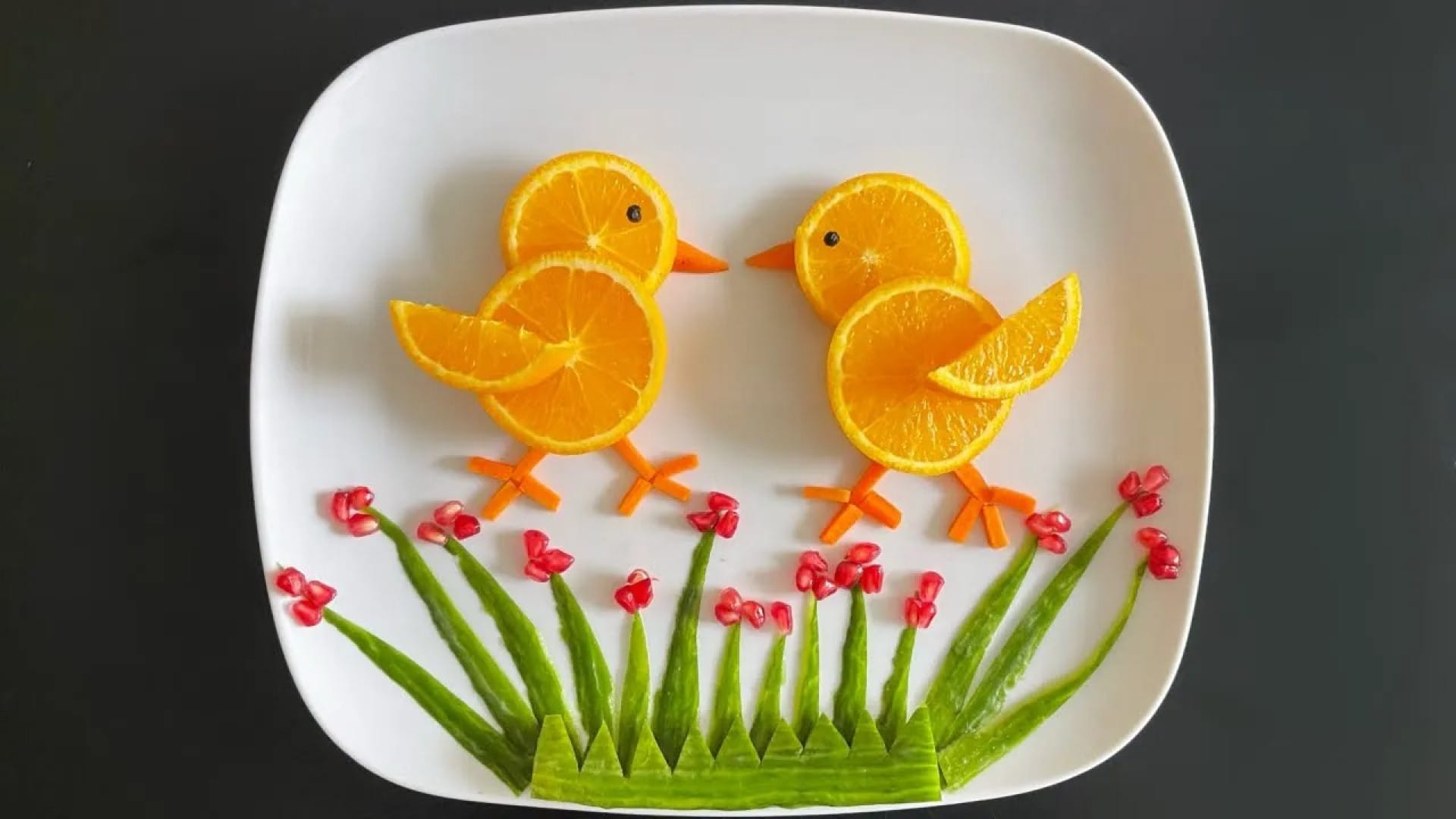 تزیین میوه به شکل جوجه بامزه روی بشقاب سفید با پرتقال و سبزیجات