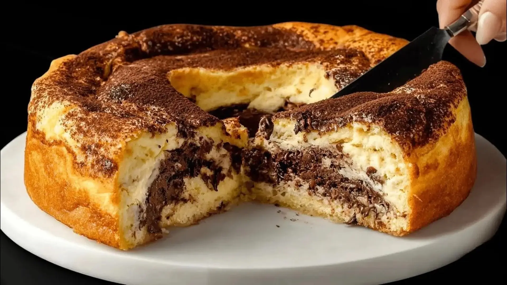 طرز تهیه کیک کاکائویی خوشمزه و اسفنجی خانگی که با چاقو برش خورده و بافت نرم آن مشخص است.