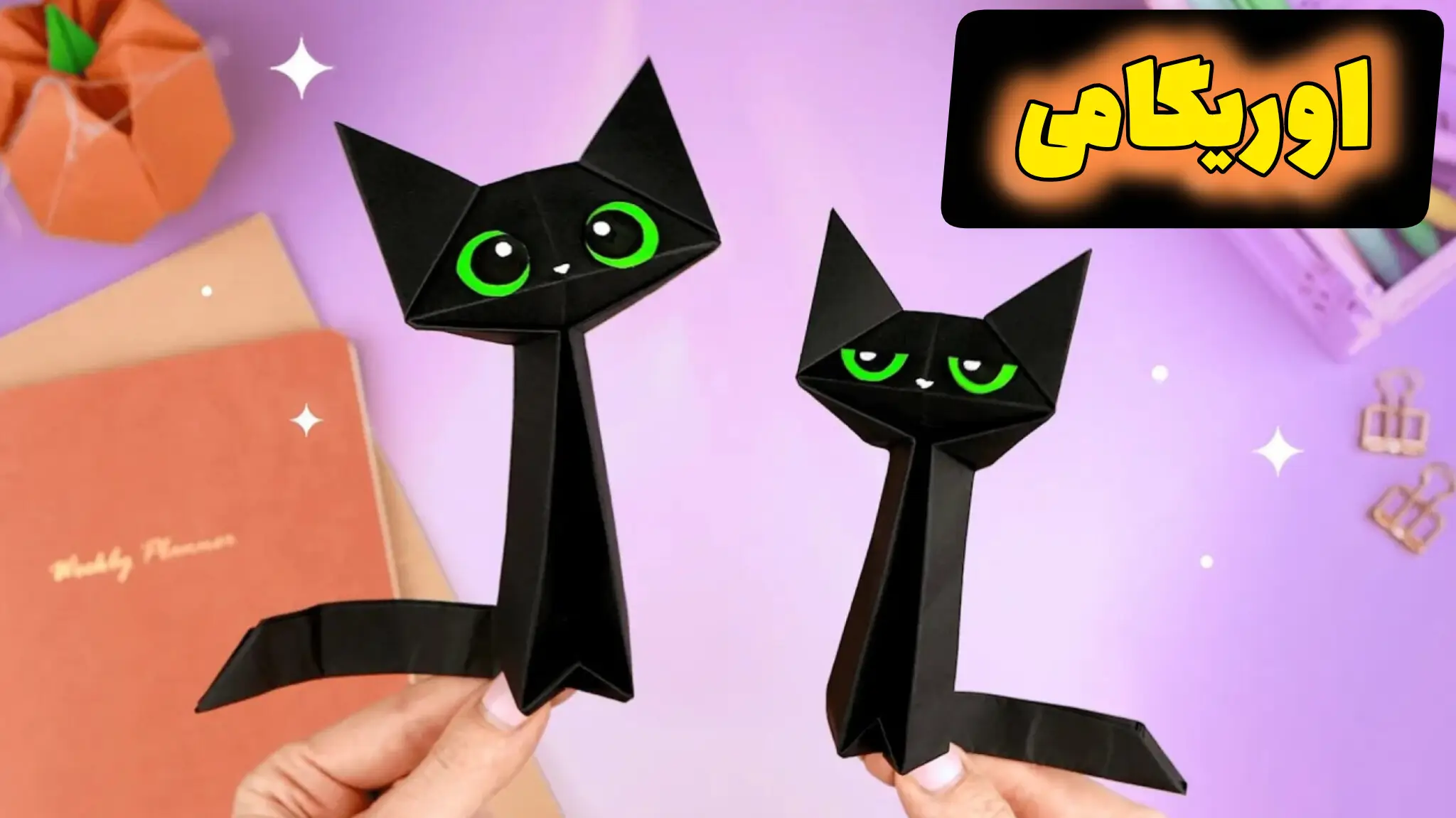 دو اوریگامی گربه سیاه با چشم‌های سبز که در دست نگه داشته شده‌اند.