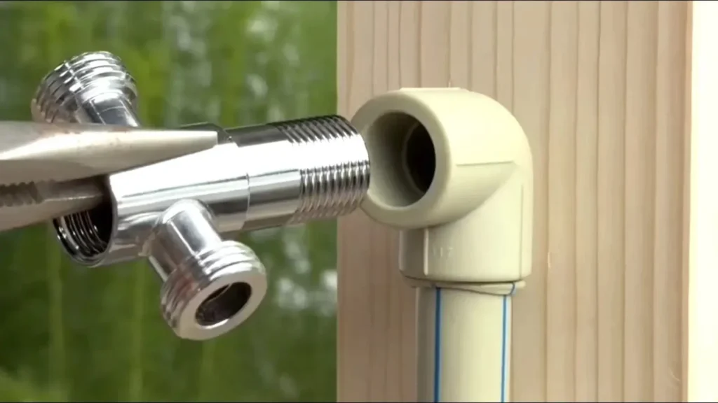 اتصال سهراهی فلزی به زانویی پلاستیکی لوله سفید با استفاده از انبردست در تعمیرات لولهکشی