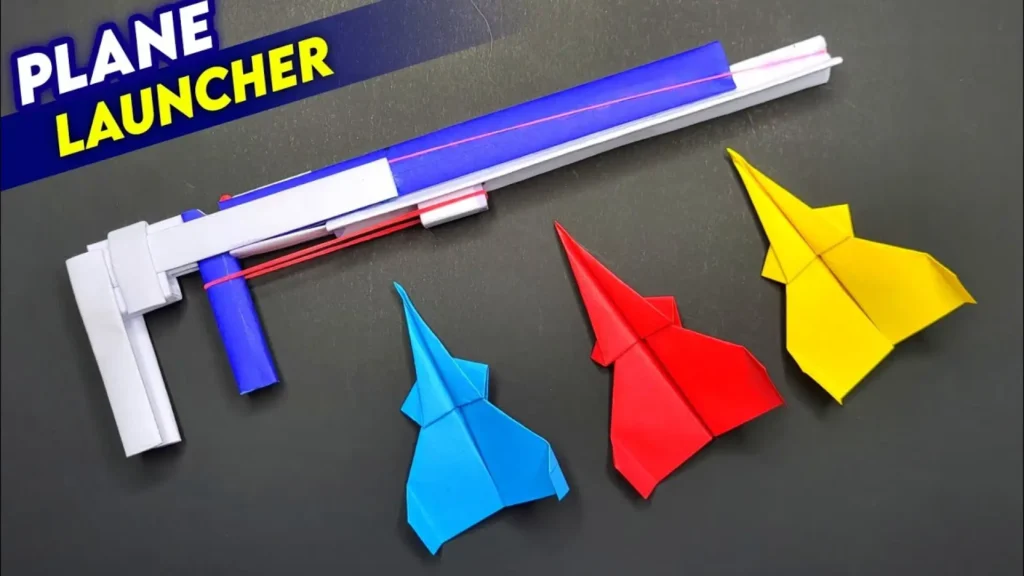 کاردستی تفنگ پرتابگر موشک کاغذی (Plane Launcher) ساخته شده با لوله‌های کاغذی و کش به همراه سه هواپیمای اوریگامی رنگی