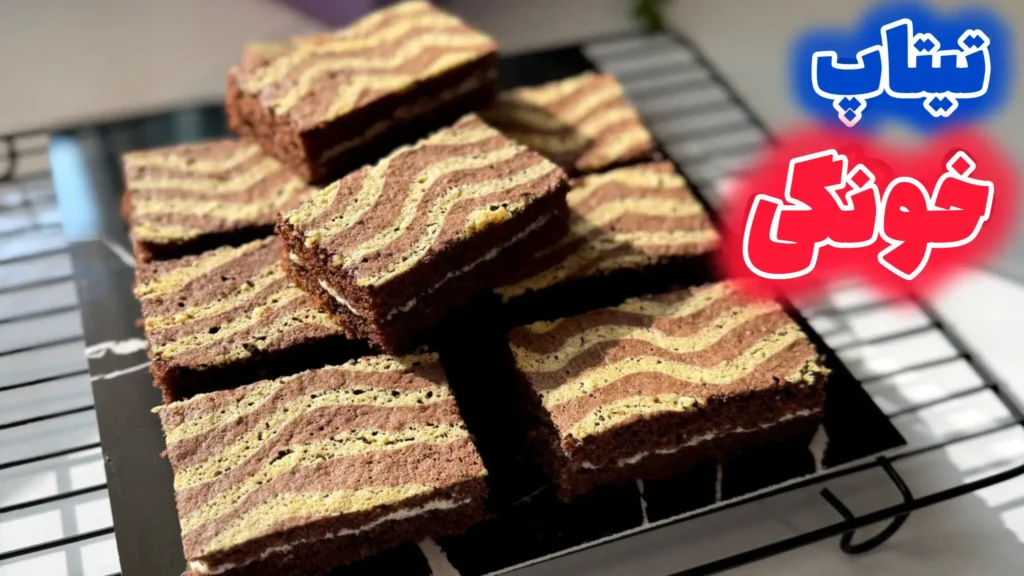 برشهای کیک تیتاپ خانگی با طرح موجدار دو رنگ شکلاتی و وانیلی و لایه کرم سفید در وسط که روی توری خنککننده چیده شدهاند.