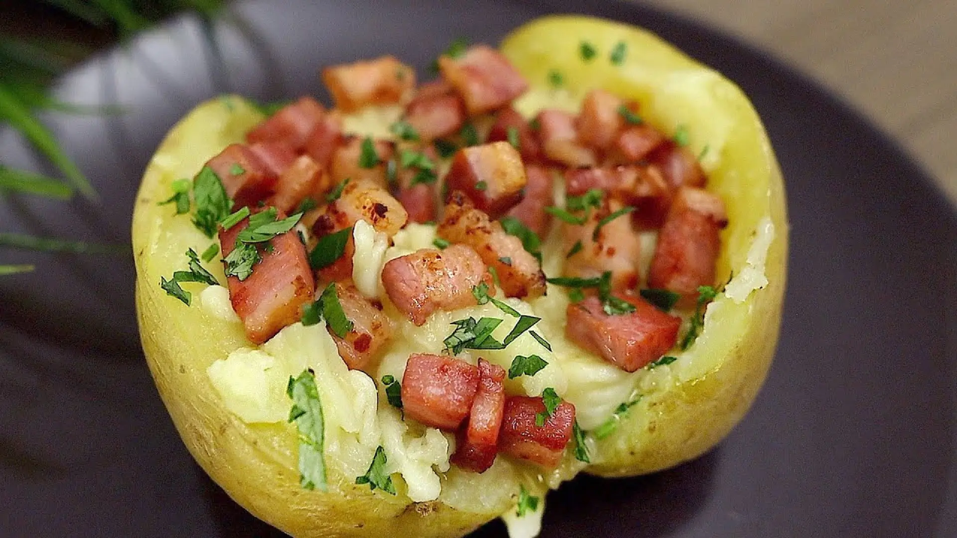 سیب‌زمینی تنوری شکم‌پر شده با پنیر پیتزا و تکه‌های بیکن سرخ‌شده و سبزیجات معطر