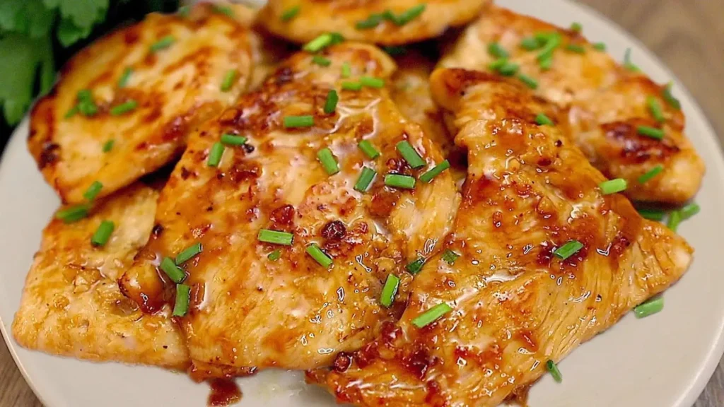 بشقاب حاوی فیله‌های سینه مرغ سرخ‌شده و براق با تزیین پیازچه خرد شده