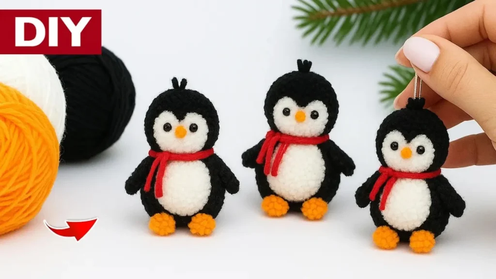 یک عروسک پنگوئن دست‌ساز که با استفاده از تکنیک پوم پوم و کاموای مشکی و سفید ساخته شده و کلاه و شالگردن آبی به تن دارد.