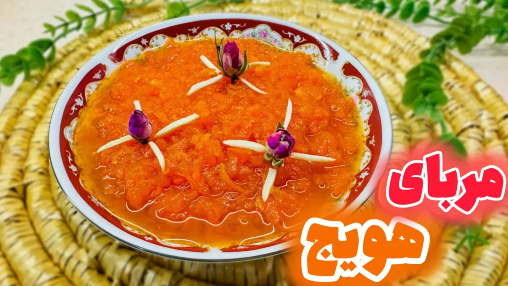 کاسه‌ای از مربای هویج خانگی خوشرنگ که با خلال بادام و غنچه گل محمدی تزیین شده و روی یک زیربشقابی حصیری قرار دارد.