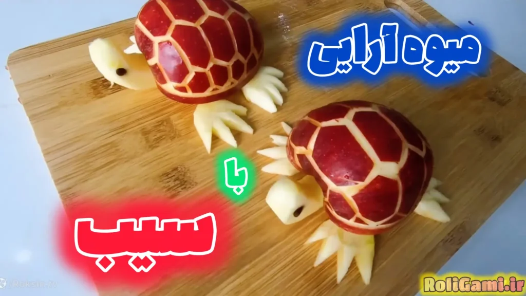 دو لاک پشت تزیینی که با سیب قرمز ساخته شدهاند؛ لاک آنها با تراشیدن پوست سیب طرحدار شده و سر و دست و پایشان با گوشت سیب روی تخته چوبی قرار گرفته است.