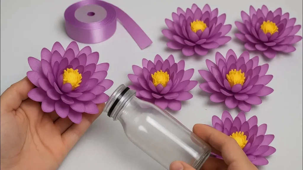 گل‌های نیلوفر دست‌ساز بنفش با مغزی زرد ساخته شده از روبان ساتن برای تزیین بطری شیشه‌ای