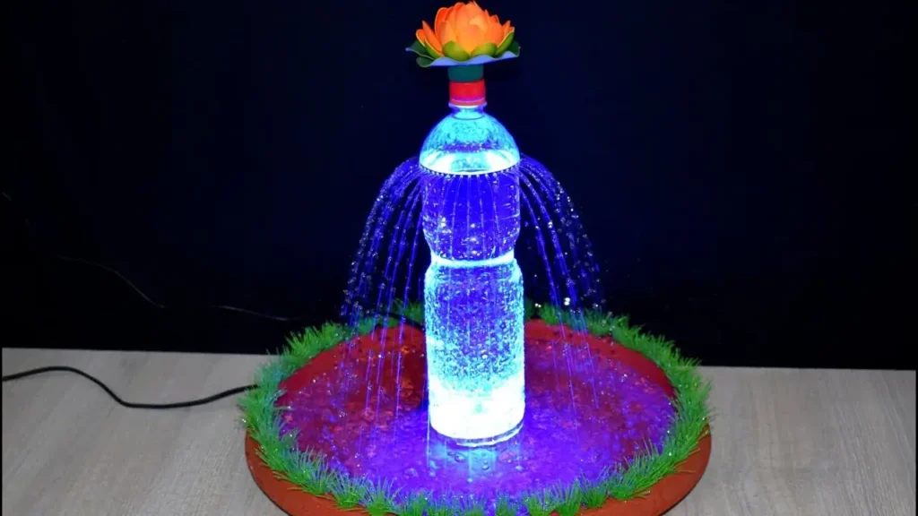 آب‌نمای دست‌ساز خانگی ساخته شده با بطری پلاستیکی نوشابه و نورپردازی LED آبی در تاریکی.