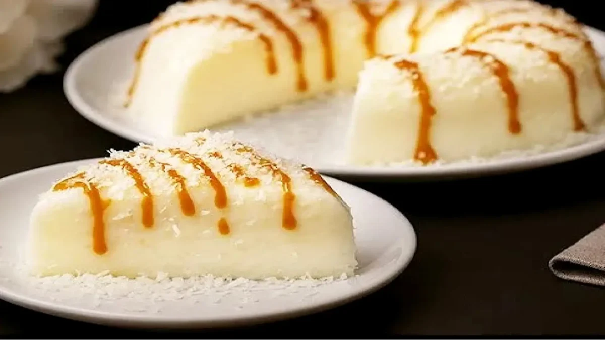 دسر قالبی سفید رنگ نارگیلی با تزیین سس کارامل و پودر نارگیل برش خورده در بشقاب