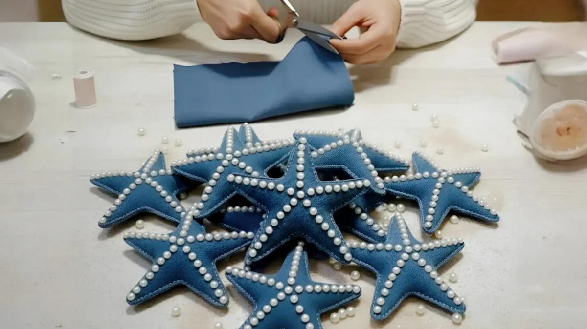 مراحل ساخت کاردستی ستاره دریایی با پارچه جین آبی و تزیین مروارید سفید روی میز کار