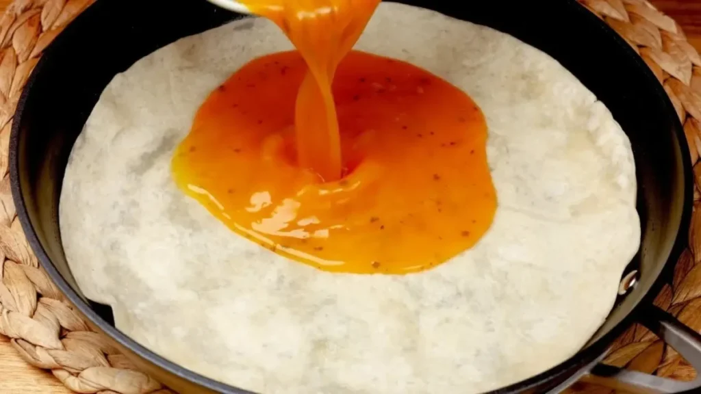 ریختن مایع تخم مرغ هم زده روی نان تورتیلا داخل تابه تفلون برای پخت صبحانه فوری