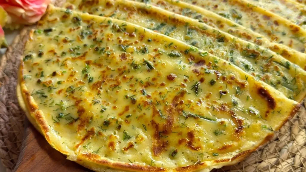 چند لایه کرپ پنیر و سبزیجات طلایی و برشته روی هم چیده شده با بافت نرم و تکههای سبزی معطر