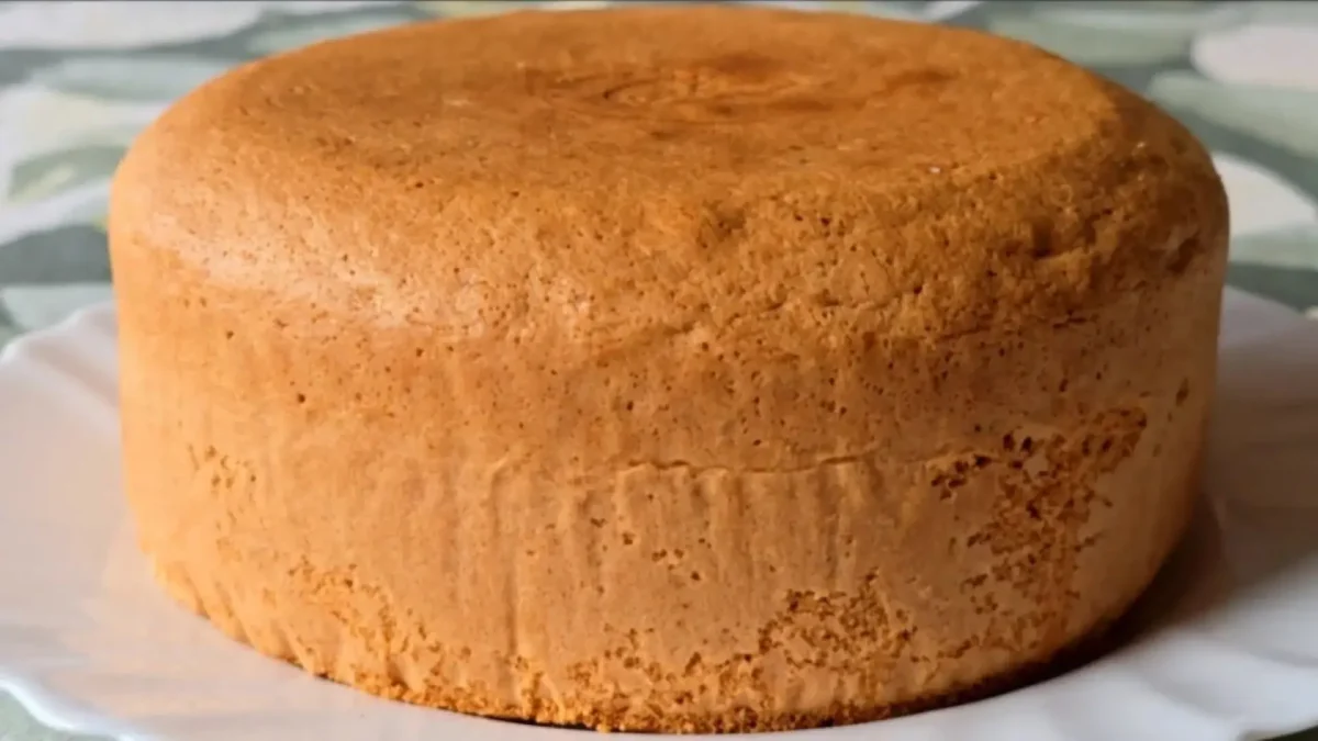 کیک اسفنجی پرتقالی ساده با پف زیاد و رنگ طلایی روی بشقاب سفید آماده سرو