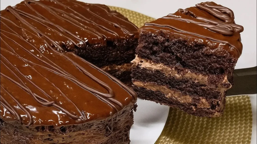 برش مثلثی از کیک شکلاتی لایهای پراگ با بافت اسفنجی تیره و فیلینگ کرم کاکائویی و روکش شکلات براق